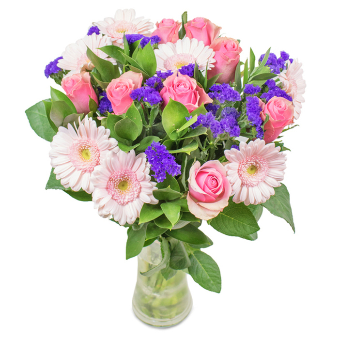 An elegantly arranged floral bouquet, freshly gathered by expert florists in Cranham and thoughtfully presented in a crystal-clear glass vase against a pure white background. The centerpiece glows with the presence of seven to nine soft and medium pink roses-some delicately closed, others just beginning to open-displaying their classic, spiral-formed petals with quiet grace. These roses are tastefully paired with five to seven luminous pale-pink gerbera daisies, their oversized heads edged by ruffled petals and softly blushed centres, bringing light and openness to the display. Interwoven among the feature flowers are clusters of intensely coloured purple statice, whose dense form and saturated hue provide dramatic depth and lively contrast. Lush, deep-green foliage forms a verdant base, imparting a sense of abundance and freshness akin to a walk through Cranham's leafy lanes. Water and stems are clearly visible within the vase, heightening the arrangement's sense of natural immediacy-perfect for a fresh gift or local flower delivery. Suitable for birthdays, anniversaries, or as an uplifting addition to a Cranham home office, this bouquet conveys joy, affection, and the timeless beauty found in locally grown flowers.